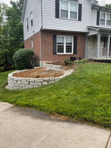 A brick house with a stone wall in front of it.