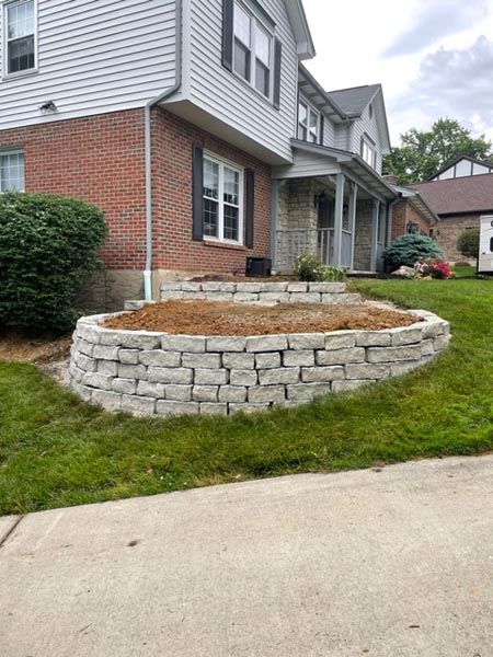A brick wall is being built in front of a brick house.