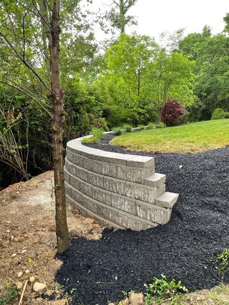 A stone wall is sitting on top of a hill next to a tree.