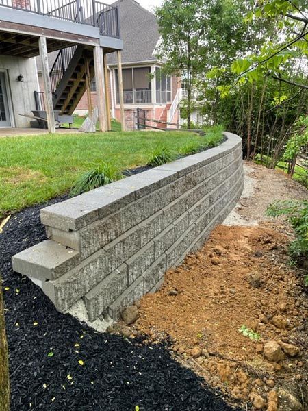 A brick wall is being built in the backyard of a house.