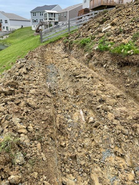 A dirt road going up a hill next to a house.