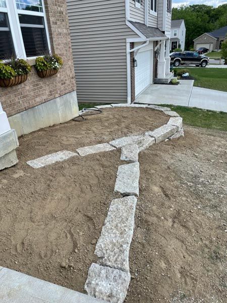 A stone walkway is being built in front of a house.