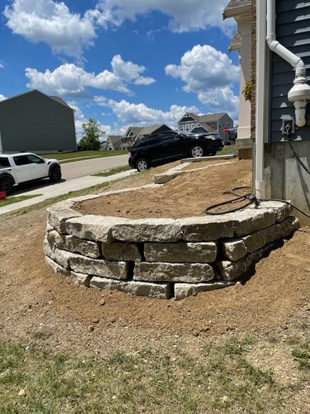 A stone wall is being built in front of a house.