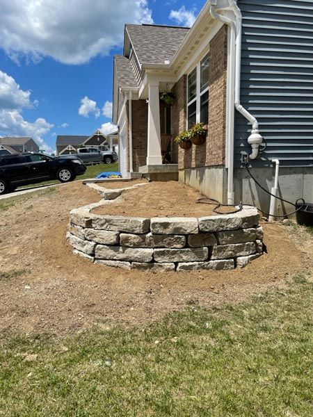A stone wall is being built in front of a house.