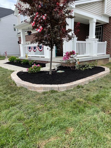 A house with a porch and a tree in front of it.
