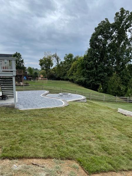 A lush green lawn with a patio and a house in the background.