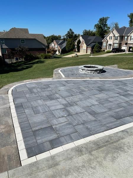 A brick driveway with a fire pit in the middle of it