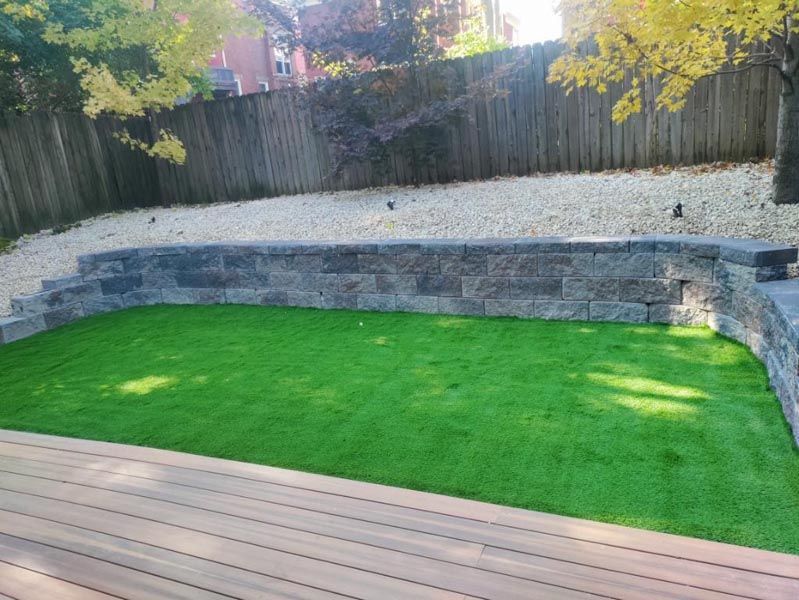 A backyard with a wooden deck and a lush green lawn.