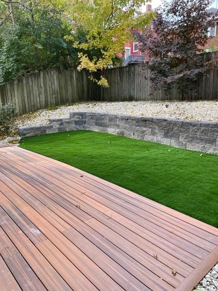 A wooden deck is sitting on top of a lush green lawn in a backyard.