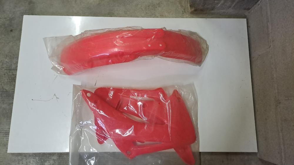 Un parafango rosso e una copertura per parafango rossa sono appoggiati su un tavolo bianco.