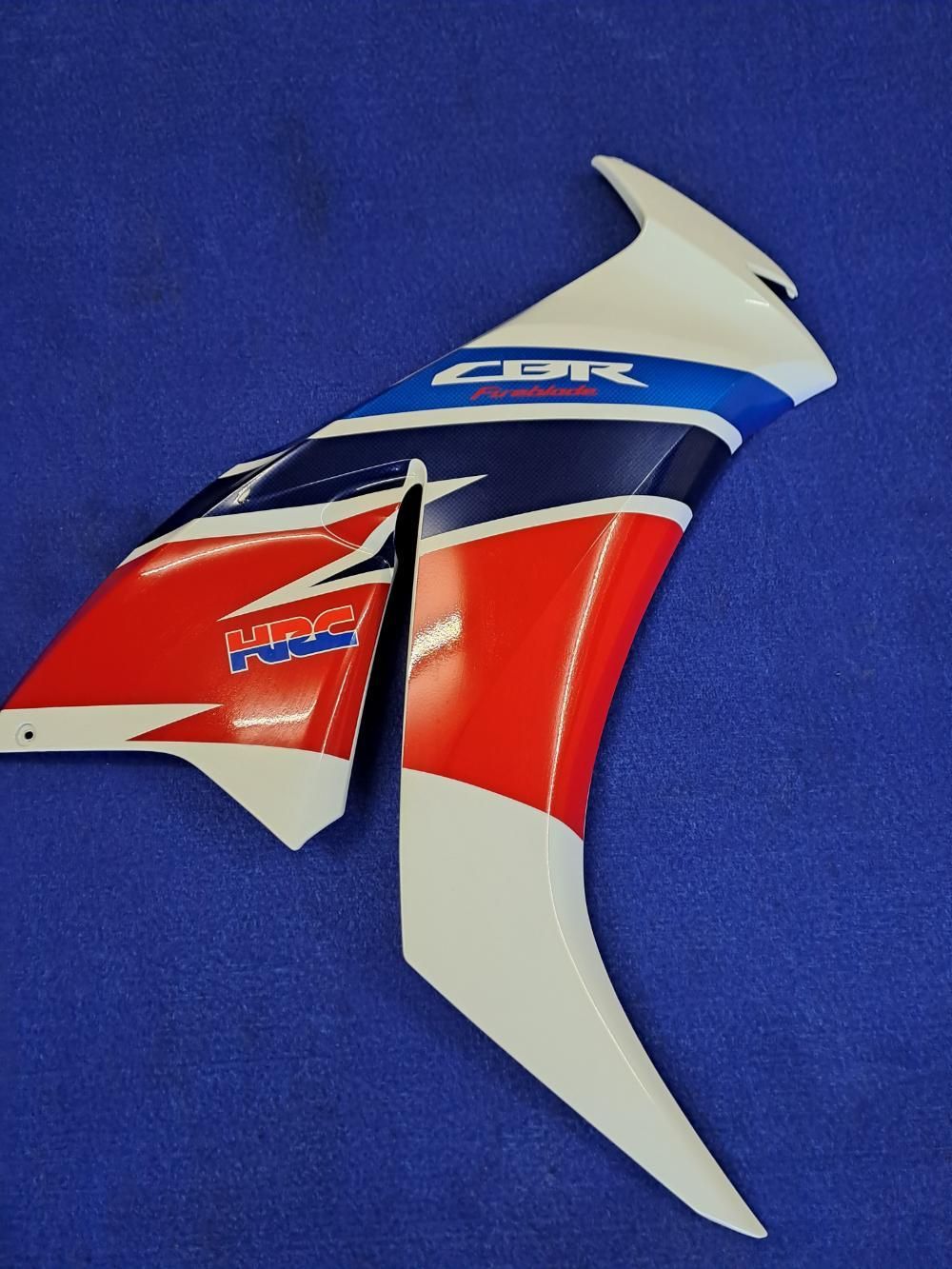 Una motocicletta rossa, bianca e blu è seduta su una superficie blu