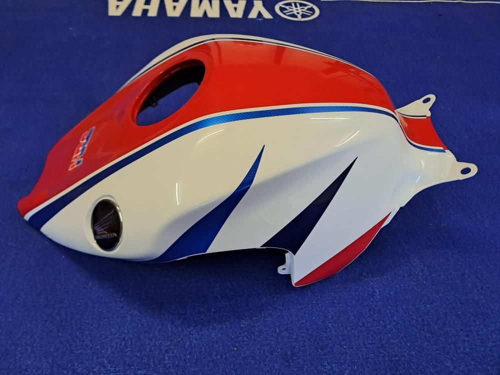 Un serbatoio Yamaha rosso, bianco e blu è appoggiato su una superficie blu