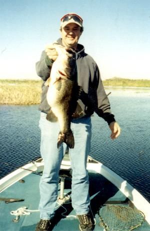 A man on a boat holding a large fish