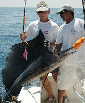 two men on a boat holding a large sailfish