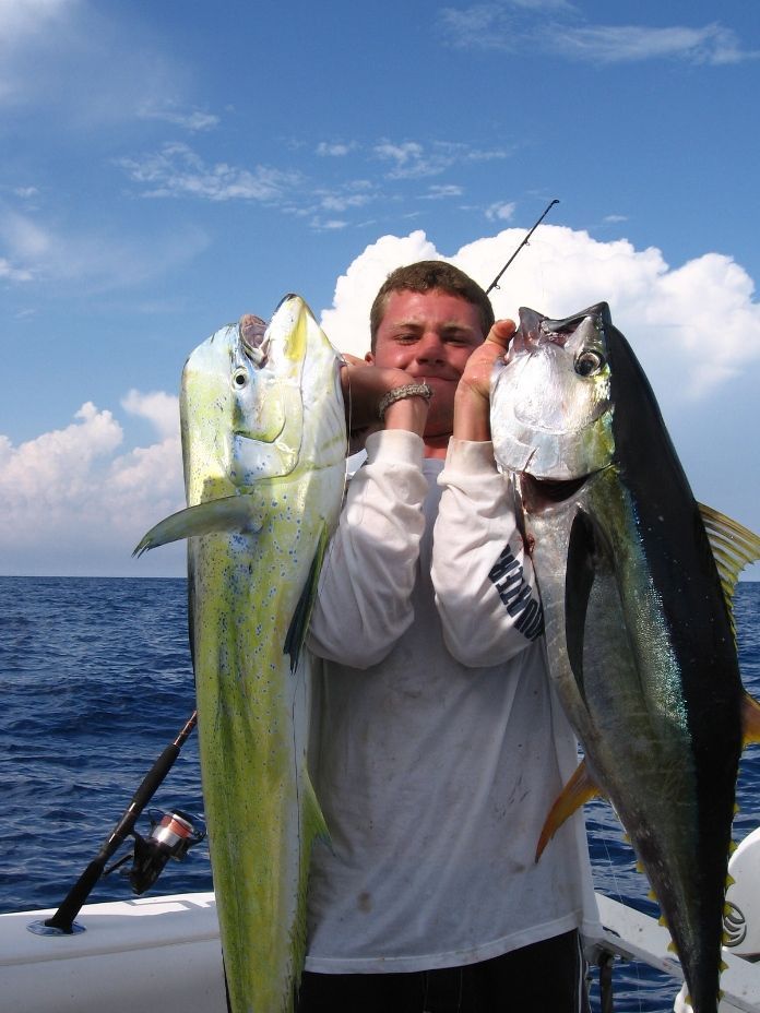 a man in a white shirt is holding two fish in his hands