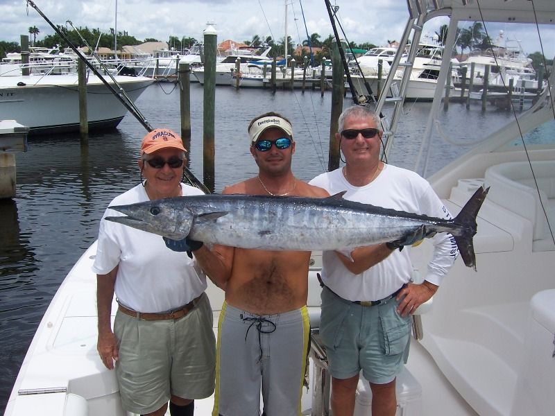 Three men standing on a boat holding a large fish