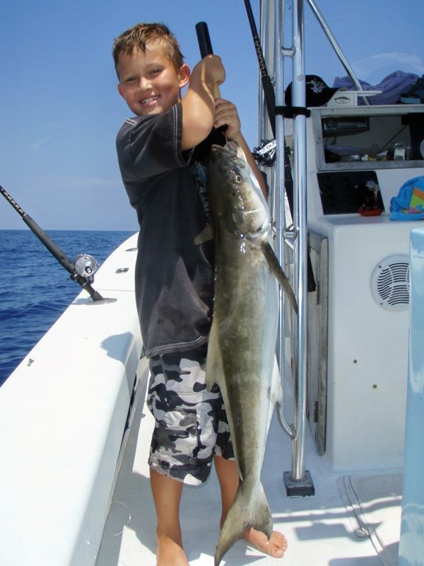 A young boy is holding a large fish on a boat