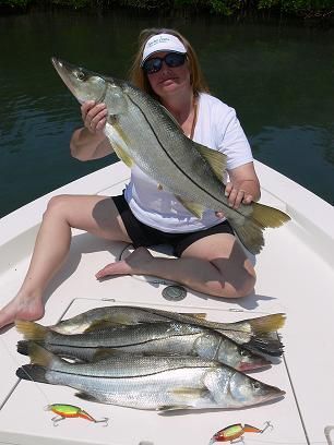 A woman is sitting on a boat holding a large fish.