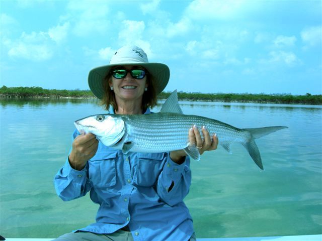 a woman in a hat is holding a fish in her hands