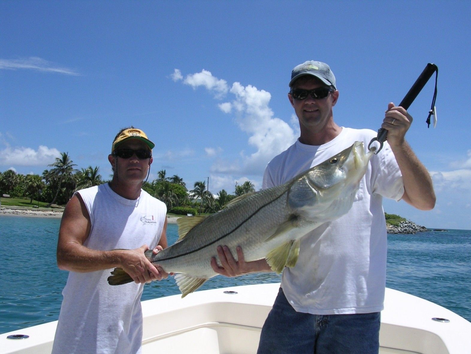 Two men on a boat holding a large fish