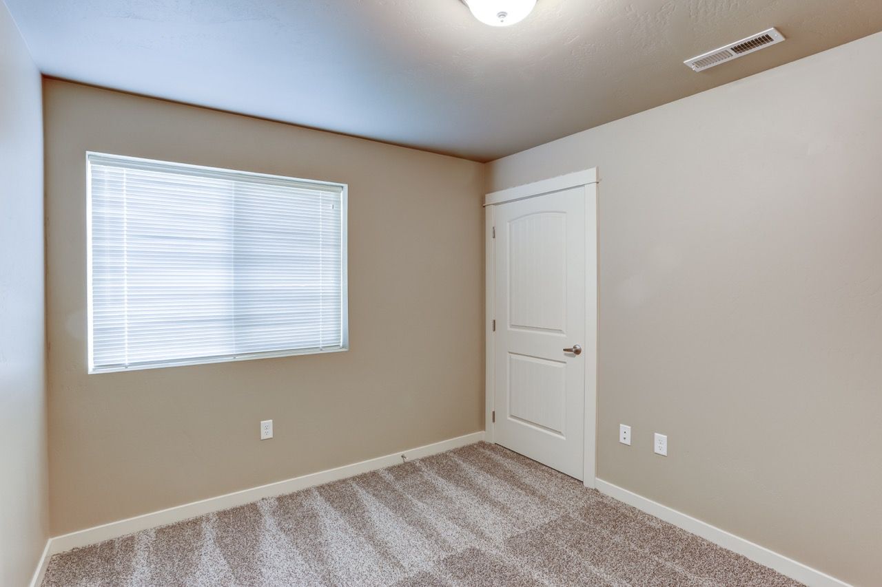 Interior room with window blinds, a white door, beige walls, and carpet.