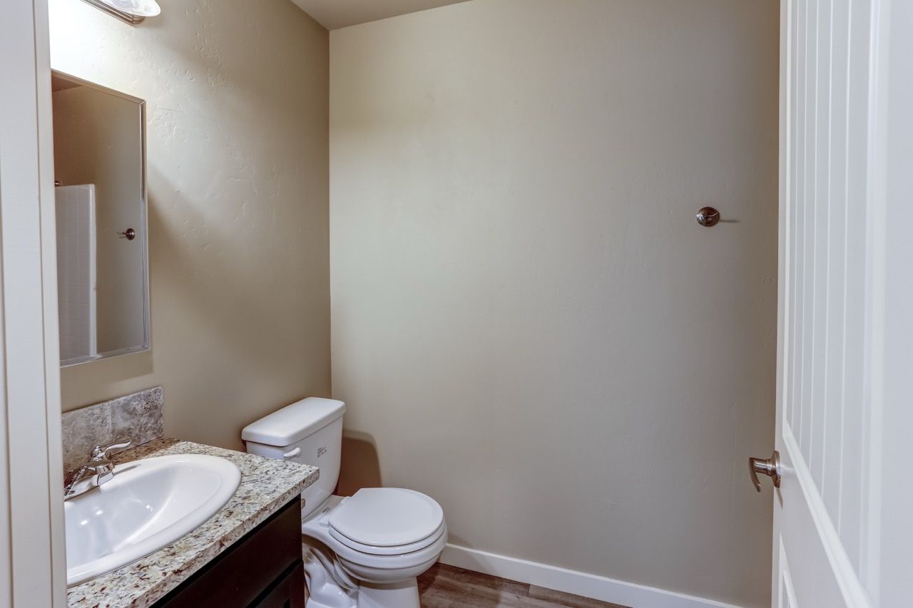 Bathroom with sink, granite countertop, mirror, and toilet.