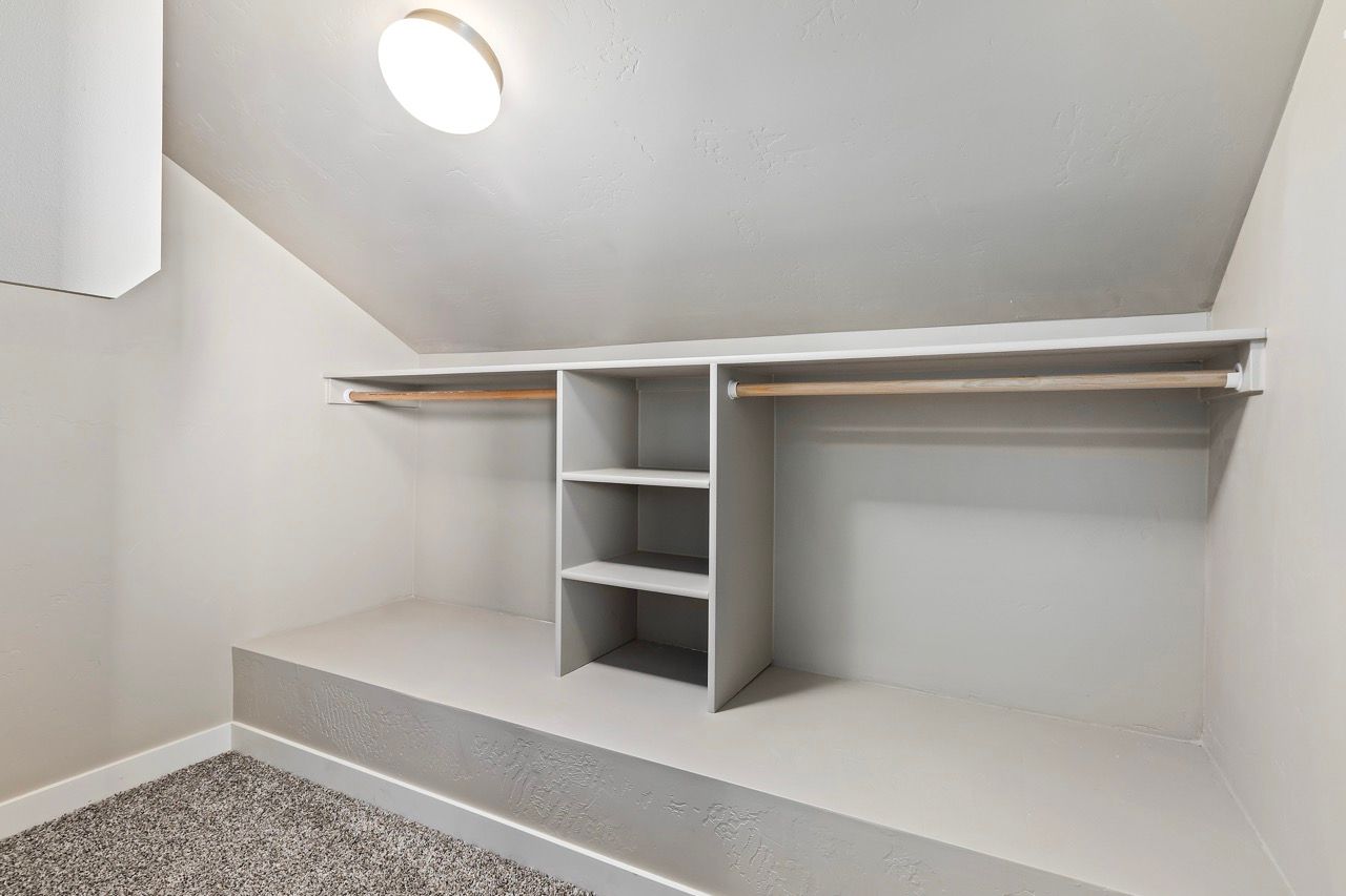 Closet with dual hanging rods and central shelving under a sloped ceiling.