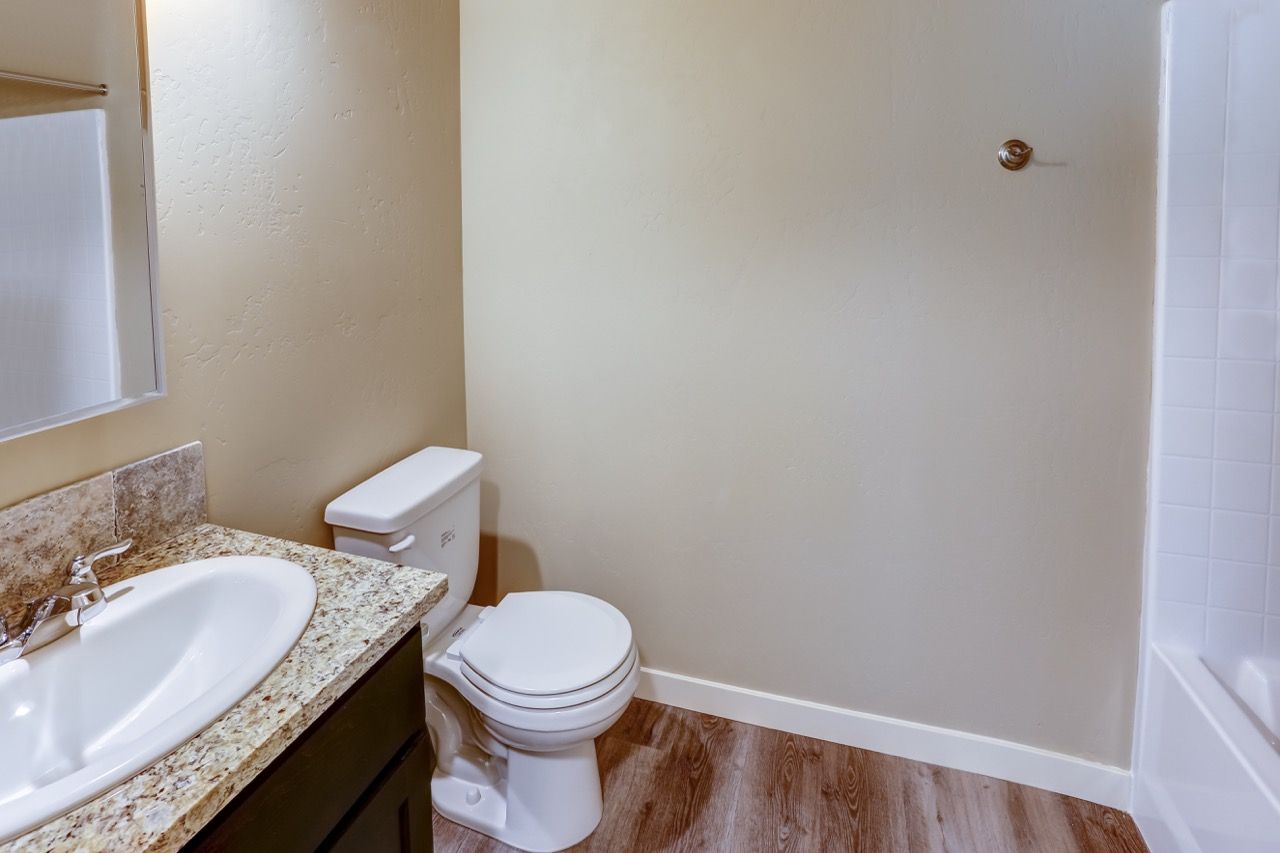 Bathroom in an apartment with granite vanity, sink, toilet, and tub/shower.