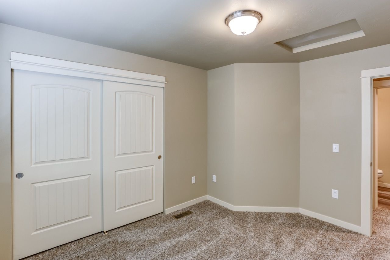 Bedroom with beige walls, carpet, and sliding closet doors.