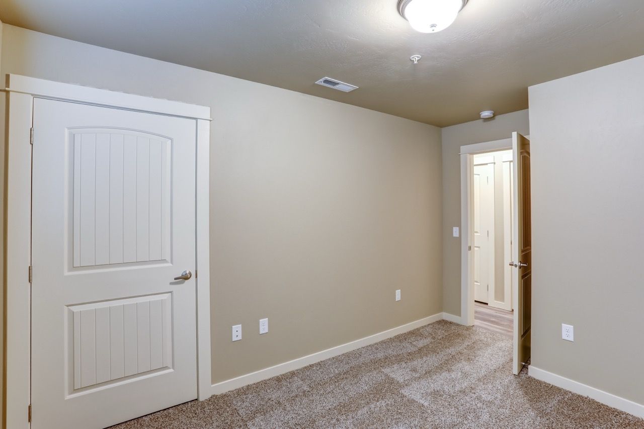 Neutral beige apartment bedroom with carpet and white panel doors.