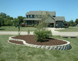 Suburban house with a landscaped front yard, curved mulch bed, and small shrub near the driveway.