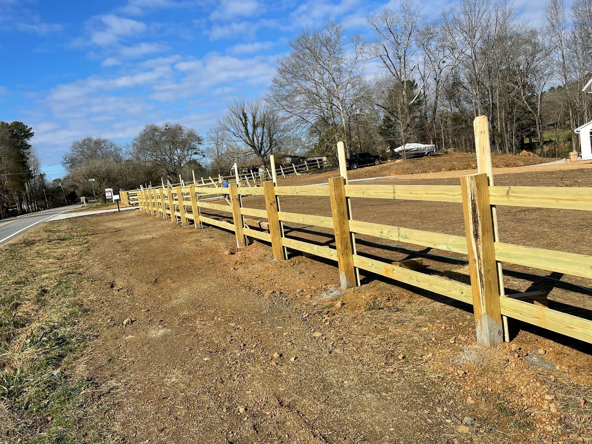 Wooden fence along a grassy roadside under a clear blue sky