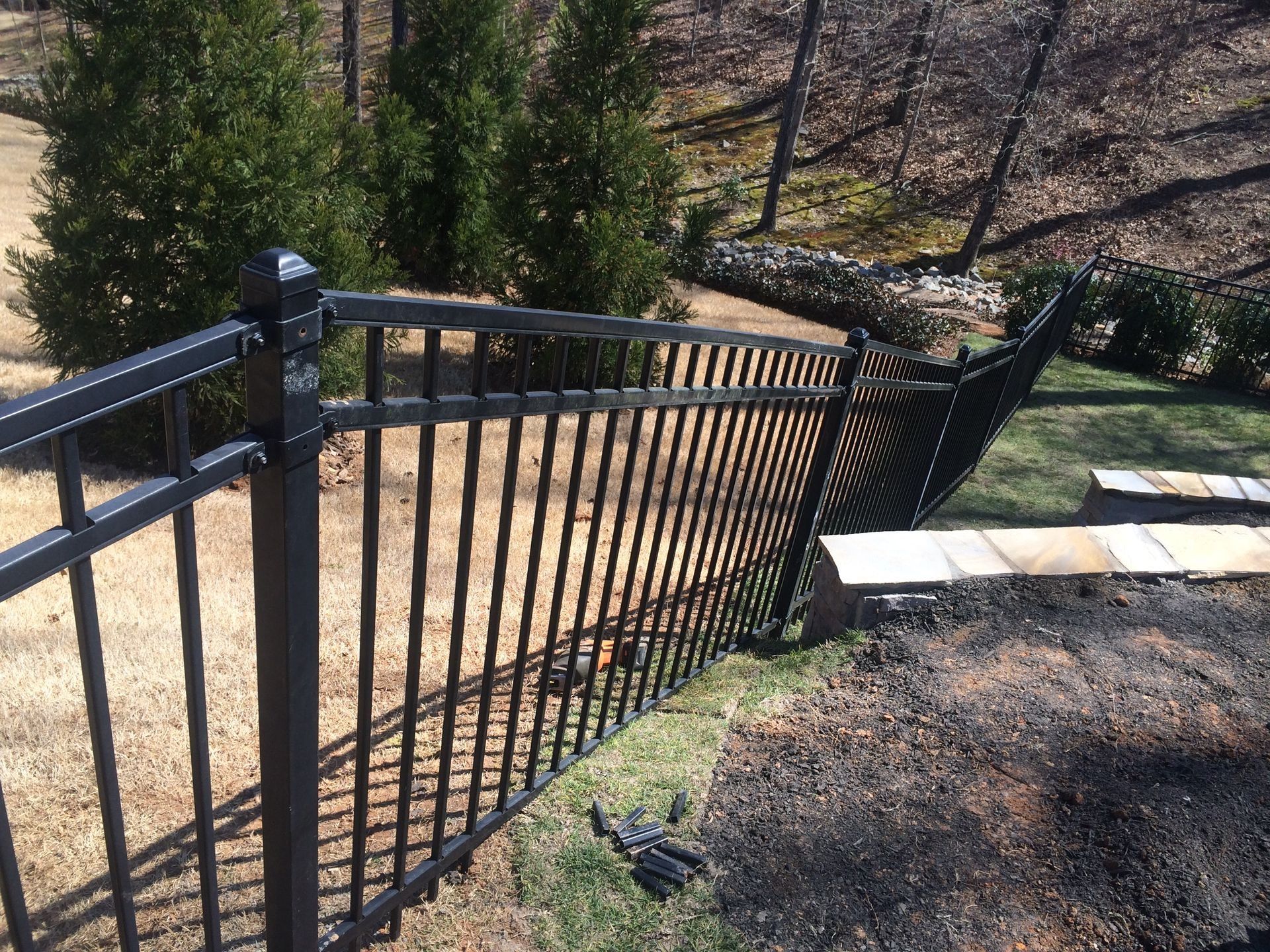 Black metal stair railing beside a concrete path in a landscaped garden