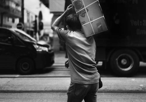A man carrying a package with bundlings of plastic.