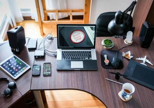 A desk with Electronics and Computers in an office.