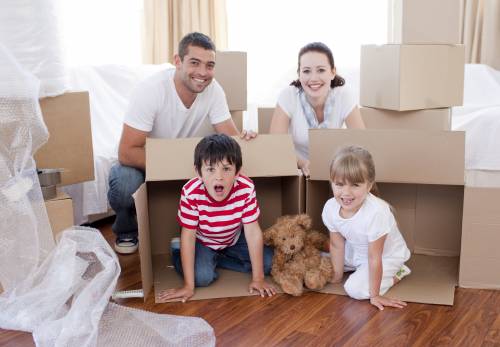 A family is playing in cardboard boxes in a new home.