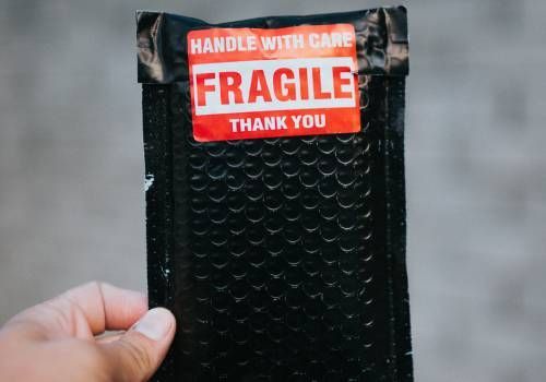 A human holding a fragile labelled package.