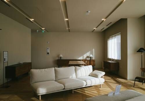 A living room with a large white sofa on the middle. 