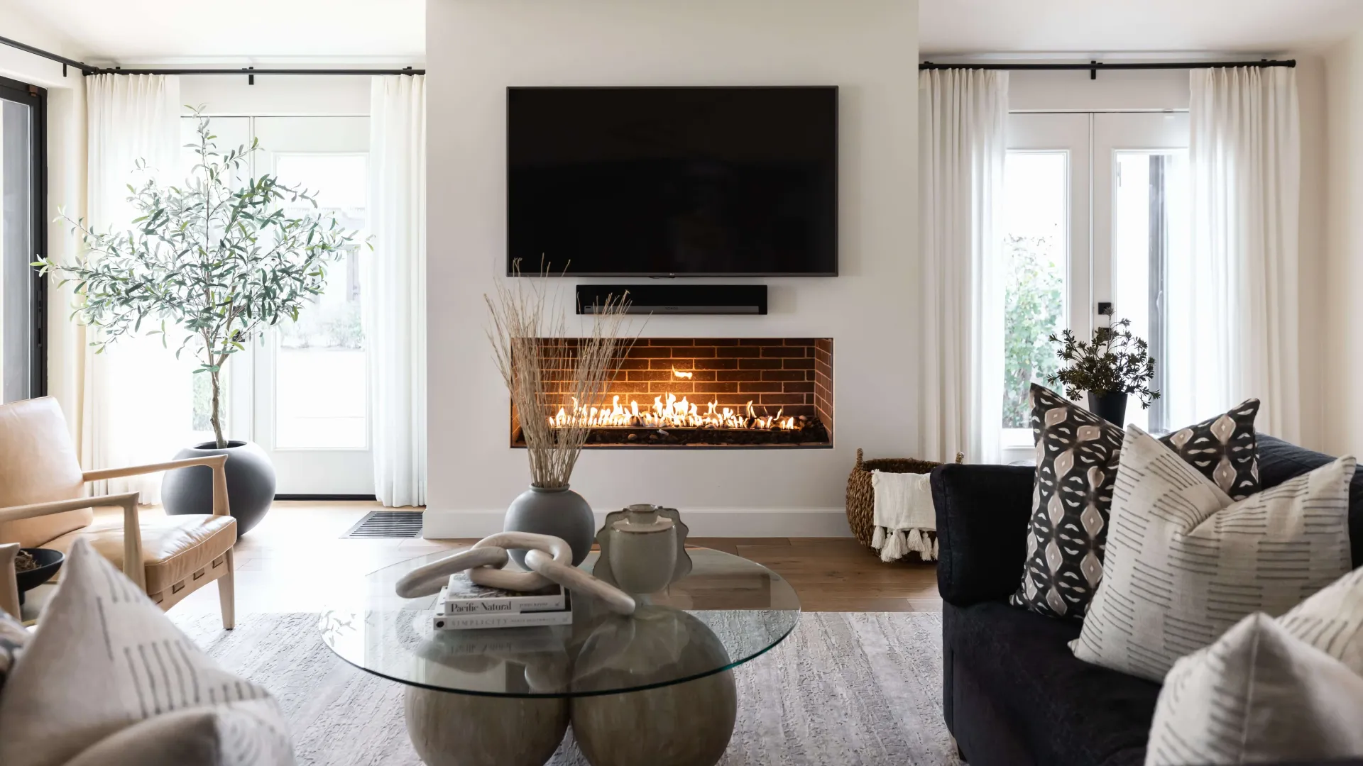 Living room with fireplace, TV, sofa, coffee table, and sheer curtains.