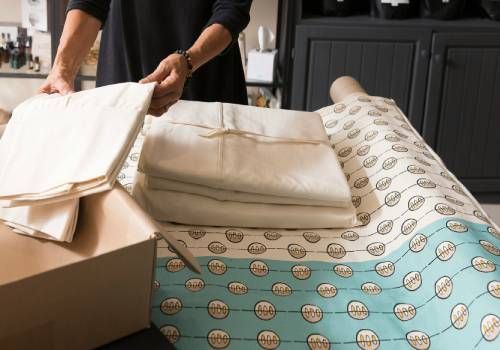 A man folding sheets for mattresses.