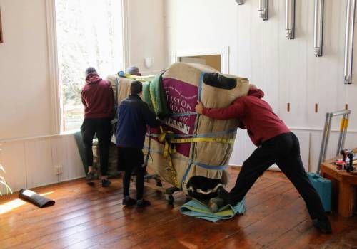Three men moving a large mattress.