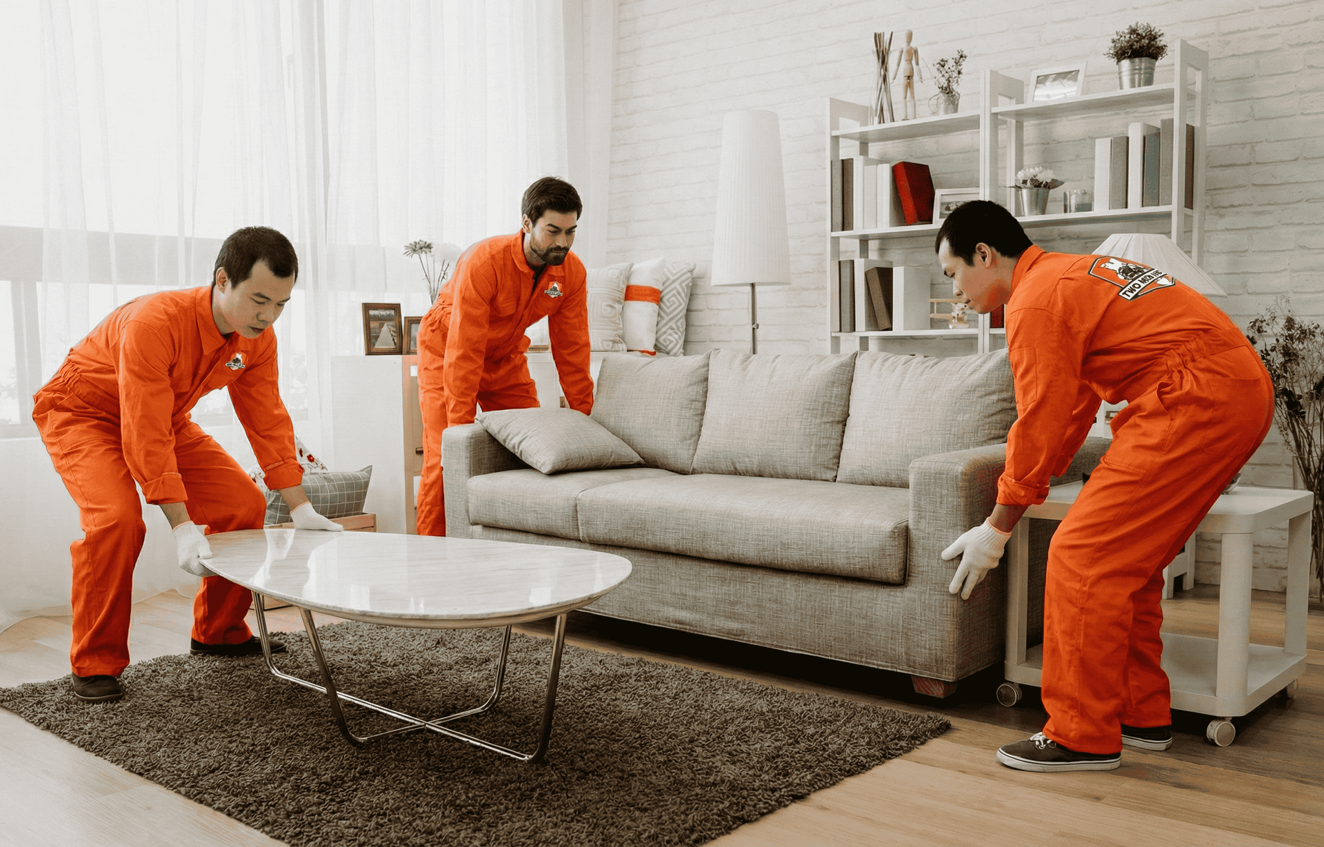 Movers repositioning furniture to create more space in a modern living room