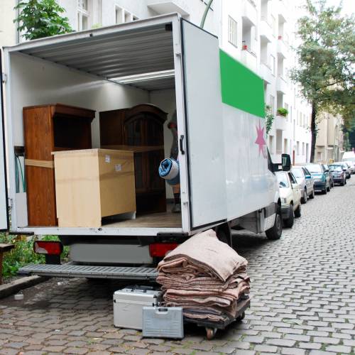 A moving truck is parked on a cobblestone street