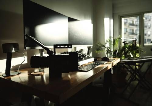 An image of an office with dual monitor screens showered by afternoon glow.