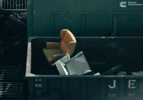 A dump truck carrying two lounge chairs. 