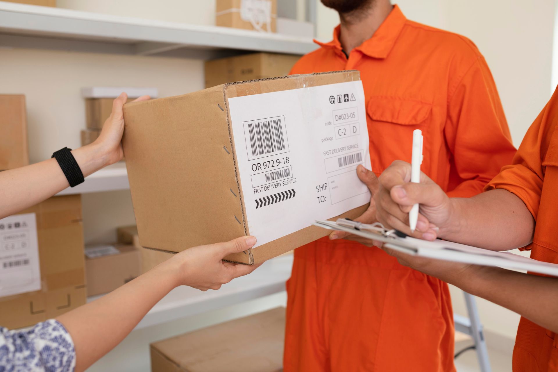 People in orange jumpsuits handing a package to someone, a clipboard for a signature.