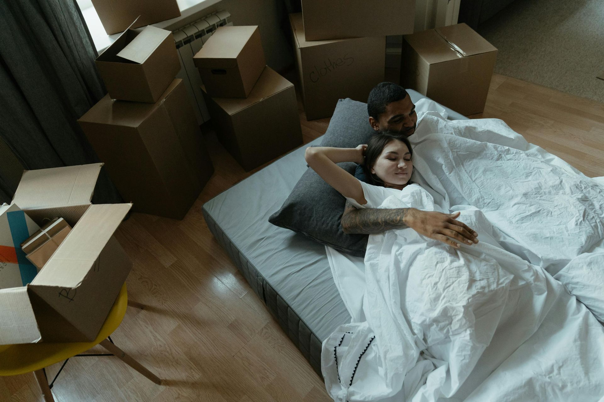 Three men moving a large mattress.