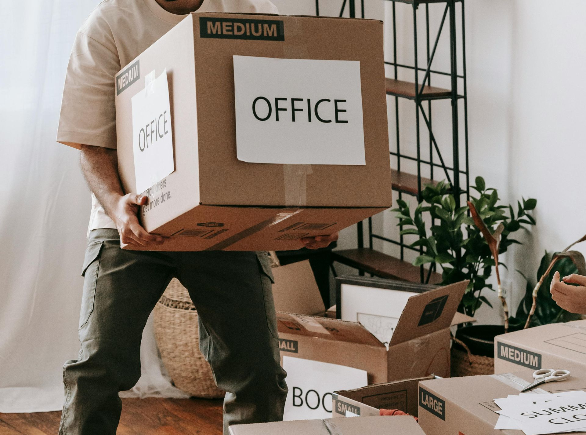 A person carrying a cardboard box labeled 
