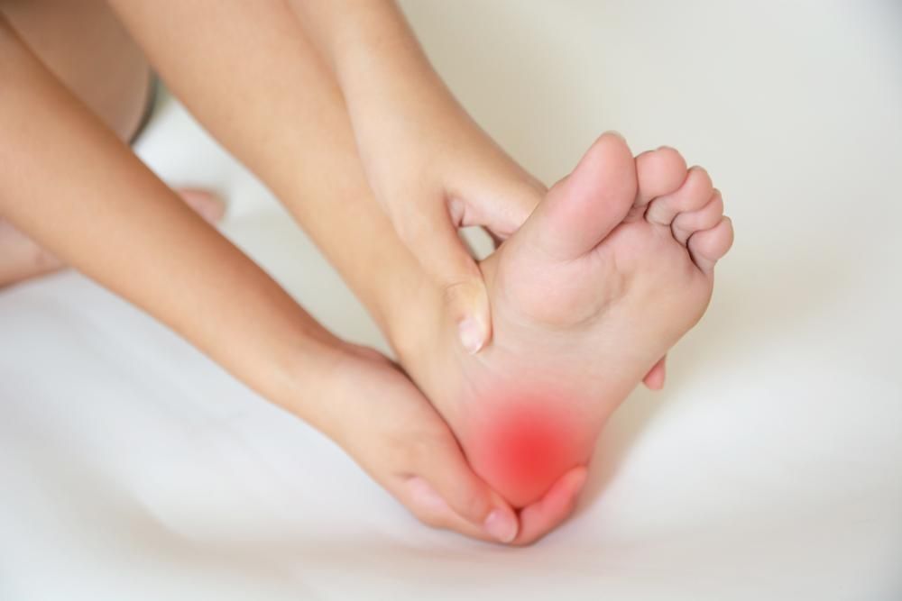 A Person Is Holding Their Foot In Pain — Port Macquarie Physio & Pilates In Port Macquarie, NSW