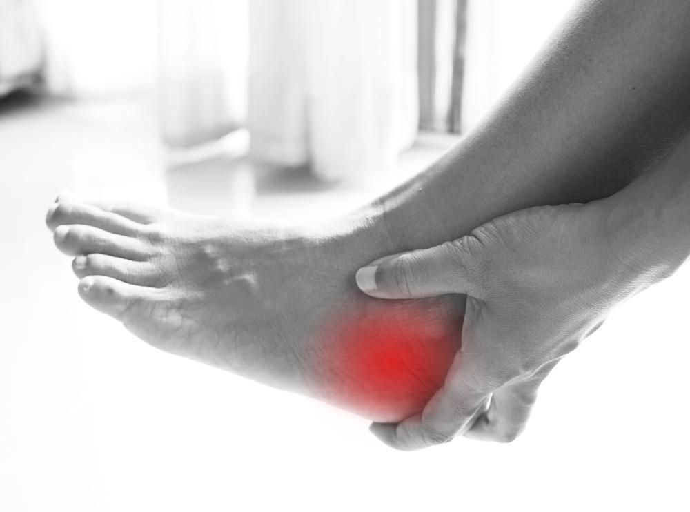 A Person Is Holding Their Foot In Pain — Port Macquarie Physio & Pilates In Port Macquarie, NSW